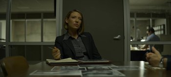 Movie still from “Mindhunter” (2017), directed by Tobias Lindholm – A woman sitting at a table in front of papers; Medium shot, Over the shoulder angle