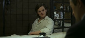 Movie still from “Mindhunter” (2017), directed by Tobias Lindholm – A man sitting at a table in front of a cell phone; Medium shot, Over the shoulder angle