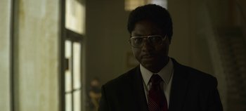Movie still from “Mindhunter” (2017), directed by Tobias Lindholm – A man in a suit and tie standing in front of a window; Close Up shot, Low angle