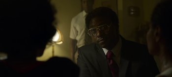 Movie still from “Mindhunter” (2017), directed by Tobias Lindholm – A man in a suit and tie sitting in front of a lamp; Close Up shot, Over the shoulder angle