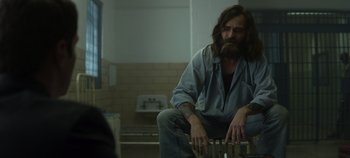 Movie still from “Mindhunter” (2017), directed by Tobias Lindholm – A man sitting in a bathroom with a beard; Medium shot, Over the shoulder angle