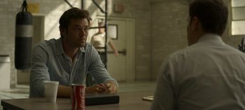 Movie still from “Mindhunter” (2017), directed by Tobias Lindholm – A man sitting at a table with a can of soda; Medium shot, Over the shoulder angle