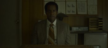 Movie still from “Mindhunter” (2017), directed by Tobias Lindholm – A man wearing a suit and tie in a room; Medium shot, Low angle