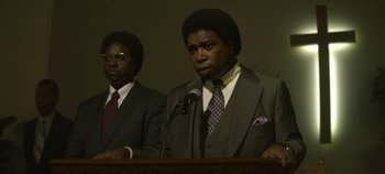 Movie still from “Mindhunter” (2017), directed by Tobias Lindholm – A man in a suit and tie standing next to another man; Medium shot, Low angle