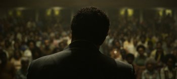 A man in a suit is looking at a crowd of onlookers