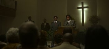 Movie still from “Mindhunter” (2017), directed by Tobias Lindholm – A group of men standing at a podium in front of a crowd; Wide shot, High angle