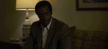 Movie still from “Mindhunter” (2017), directed by Tobias Lindholm – A man wearing a suit and tie sitting in front of a lamp; Close Up shot, Over the shoulder angle