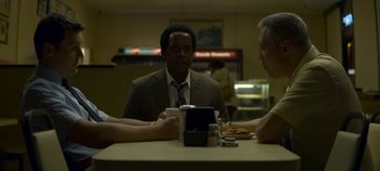 Movie still from “Mindhunter” (2017), directed by Tobias Lindholm – Three people sitting at a table with a drink; Medium shot, Over the shoulder angle