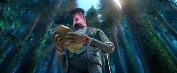 Movie still from “Missing Link” (2019), directed by Chris Butler – A man in a suit and hat holding a glove in a forest; Medium shot, Low angle