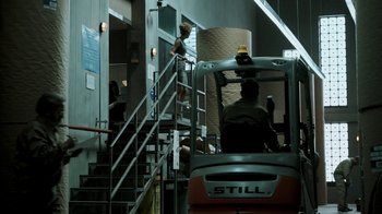 Movie still from “Money Heist” (2017), created by Álex Pina – A man standing on the stairs of a building; Wide shot, Low angle