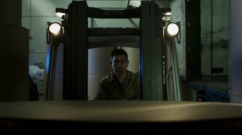 Movie still from “Money Heist” (2017), created by Álex Pina – A man sitting in a forklift in a warehouse; Wide shot, Low angle
