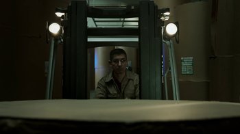 Movie still from “Money Heist” (2017), created by Álex Pina – A man sitting in a forklift in a warehouse; Medium shot, Low angle