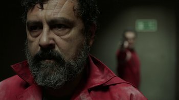 Movie still from “Money Heist” (2017), created by Álex Pina – A man with a gray beard is looking at the camera; Close Up shot, Over the shoulder angle