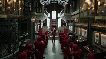 Movie still from “Money Heist” (2017), created by Álex Pina – A group of people dressed in red in a room; Extreme Wide shot, High angle