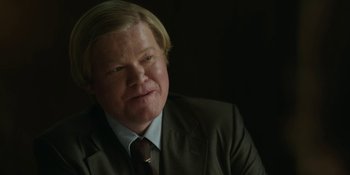 Movie still from “Love & Death” (2023), directed by Clark Johnson – A person wearing a suit and tie; Close Up shot, Over the shoulder angle