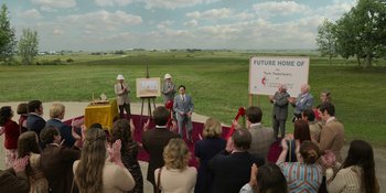 Movie still from “Love & Death” (2023), directed by Clark Johnson – A group of people standing in front of an audience; Extreme Wide shot, High angle