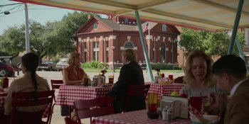 Movie still from “Love & Death” (2023), directed by Clark Johnson – Two women sitting at a table in front of a red and white checkered table cloth; Wide shot, Over the shoulder angle