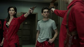 Movie still from “Money Heist” (2017), created by Álex Pina – A man standing in front of a mirror holding a gun; Medium shot, Low angle