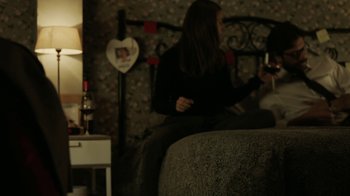 Movie still from “Money Heist” (2017), created by Álex Pina – A woman sitting on top of a bed next to a table; Medium shot, High angle