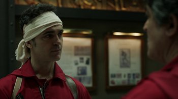 Movie still from “Money Heist” (2017), created by Álex Pina – A man with a bandage on his head; Close Up shot, Over the shoulder angle