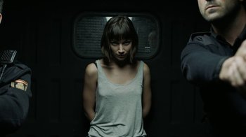 Movie still from “Money Heist” (2017), created by Álex Pina – A woman standing on a train with her hands in her pockets; Medium shot, Low angle