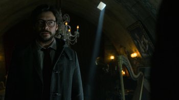 Movie still from “Money Heist” (2017), created by Álex Pina – A man standing in front of a chandelier in a dark room; Medium shot, Low angle
