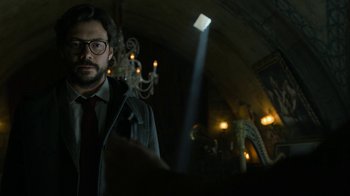 Movie still from “Money Heist” (2017), created by Álex Pina – A man in a suit and tie standing next to a chandelier; Close Up shot, Low angle