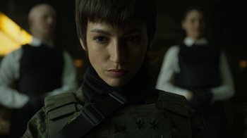 Movie still from “Money Heist” (2017), created by Álex Pina – A woman with short brown hair wearing a green jacket; Close Up shot, Over the shoulder angle