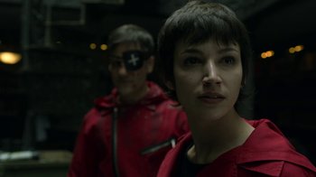 Movie still from “Money Heist” (2017), created by Álex Pina – A woman in a red jacket standing next to a man in a red jacket; Close Up shot, Over the shoulder angle
