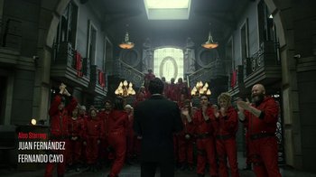 Movie still from “Money Heist” (2017), created by Álex Pina – A group of people in red suits standing in front of a building; Wide shot, Over the shoulder angle
