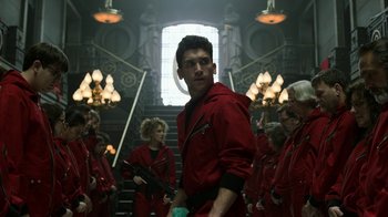 Movie still from “Money Heist” (2017), created by Álex Pina – A group of people dressed in red and holding guns; Medium shot, Low angle