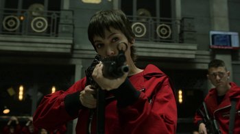 Movie still from “Money Heist” (2017), created by Álex Pina – A man in a red jacket holding a gun in his hands; Medium shot, Low angle