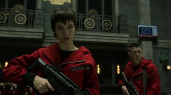 Movie still from “Money Heist” (2017), created by Álex Pina – A woman in a red jacket holding a gun; Medium shot, Low angle