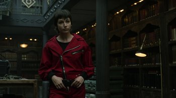 Movie still from “Money Heist” (2017), created by Álex Pina – A woman in a red jacket holding a black purse; Medium shot, Low angle