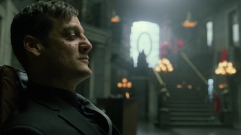 Movie still from “Money Heist” (2017), created by Álex Pina – A man wearing a suit and tie in a dark room; Close Up shot, Low angle