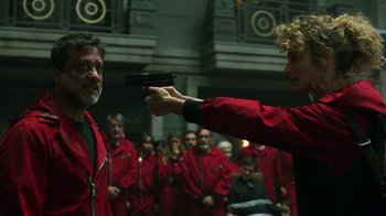 Movie still from “Money Heist” (2017), created by Álex Pina – A group of people dressed in red and holding guns; Medium shot, Over the shoulder angle