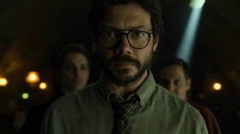 Movie still from “Money Heist” (2017), created by Álex Pina – A person wearing glasses and a tie; Close Up shot, Low angle
