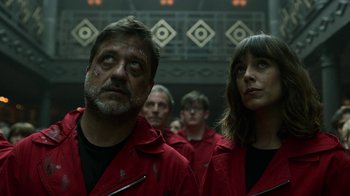 Movie still from “Money Heist” (2017), created by Álex Pina – A man and a woman wearing red shirts and looking into the distance; Close Up shot, Low angle