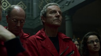 Movie still from “Money Heist” (2017), created by Álex Pina – A man in a red jacket is looking up; Close Up shot, Low angle