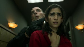 Movie still from “Money Heist” (2017), created by Álex Pina – A man holding a gun over a woman's neck; Close Up shot, Low angle