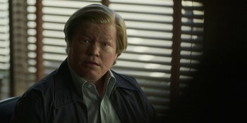 Movie still from “Love & Death” (2023), directed by Clark Johnson – A man with blonde hair wearing a blue jacket; Close Up shot, Low angle