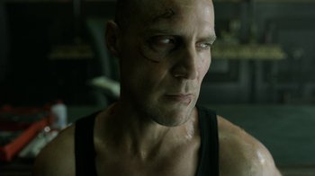 Movie still from “Money Heist” (2017), created by Álex Pina – A man with a scar on his face; Close Up shot, Low angle