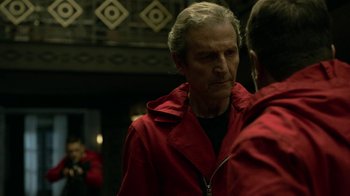 Movie still from “Money Heist” (2017), created by Álex Pina – A man in a red jacket talking to another man in a red jacket; Close Up shot, Over the shoulder angle