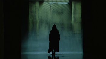 Movie still from “Money Heist” (2017), created by Álex Pina – A person standing in front of a wall in the dark; Wide shot, Low angle