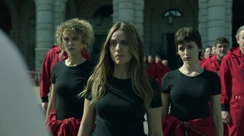 Movie still from “Money Heist” (2017), created by Álex Pina – A group of women standing next to each other in black shirts; Medium shot, Low angle