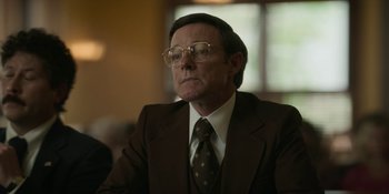 Movie still from “Love & Death” (2023), directed by Clark Johnson – An older man in a suit and tie; Close Up shot, Low angle