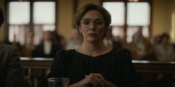 Movie still from “Love & Death” (2023), directed by Clark Johnson – A woman in a black dress is sitting at a table; Close Up shot, Low angle