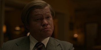 Movie still from “Love & Death” (2023), directed by Clark Johnson – A person wearing a suit and tie; Close Up shot, Low angle