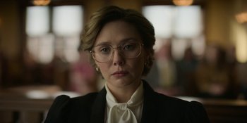 Movie still from “Love & Death” (2023), directed by Clark Johnson – A person wearing glasses and a suit; Close Up shot, Low angle