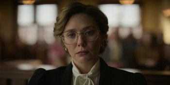 Movie still from “Love & Death” (2023), directed by Clark Johnson – A person wearing glasses and a suit; Close Up shot, Low angle
